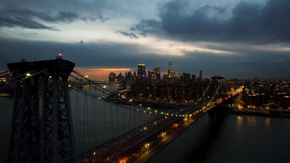 Pulling back from the bridge across the river as the city lights come on