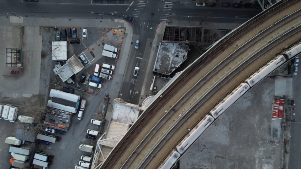 Looking straight down on an elevated train curving through a rail yard